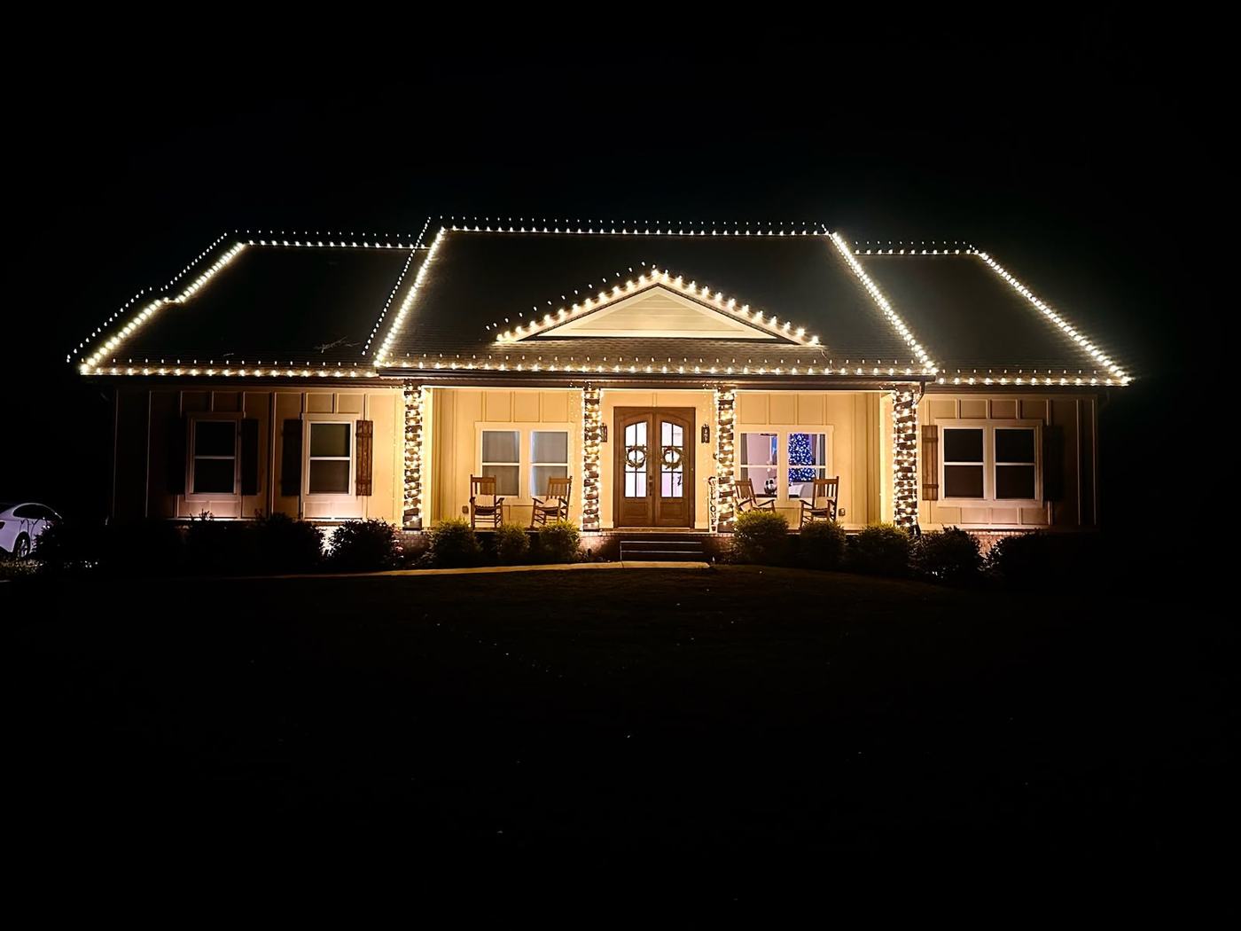 Warm white roofline and porch column lighting on a single-story Pensacola home